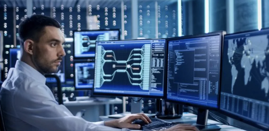 Security operator watching network and camera monitoring screens in a control room