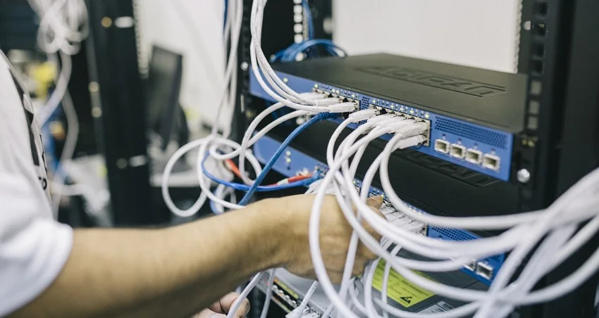 Technician patching network cables into a rack-mounted switch in a server rack