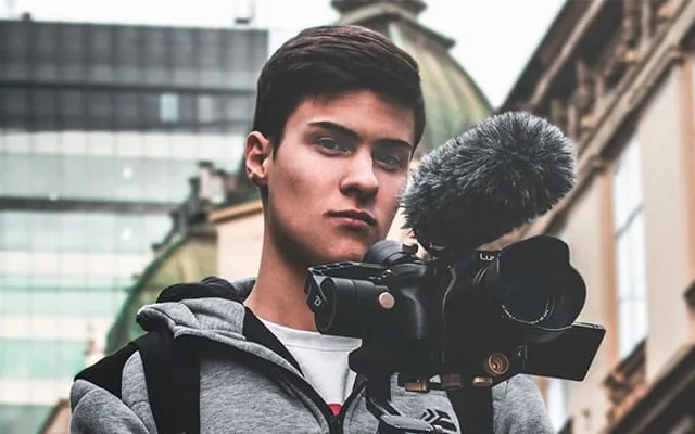 Videographer filming outdoors with a professional camera and microphone