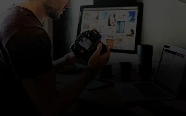 Photographer reviewing images on a laptop in a dim studio