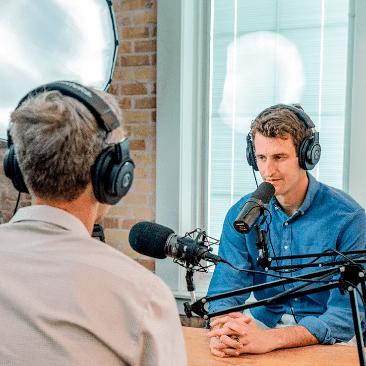 Two podcasters recording with microphones and headphones