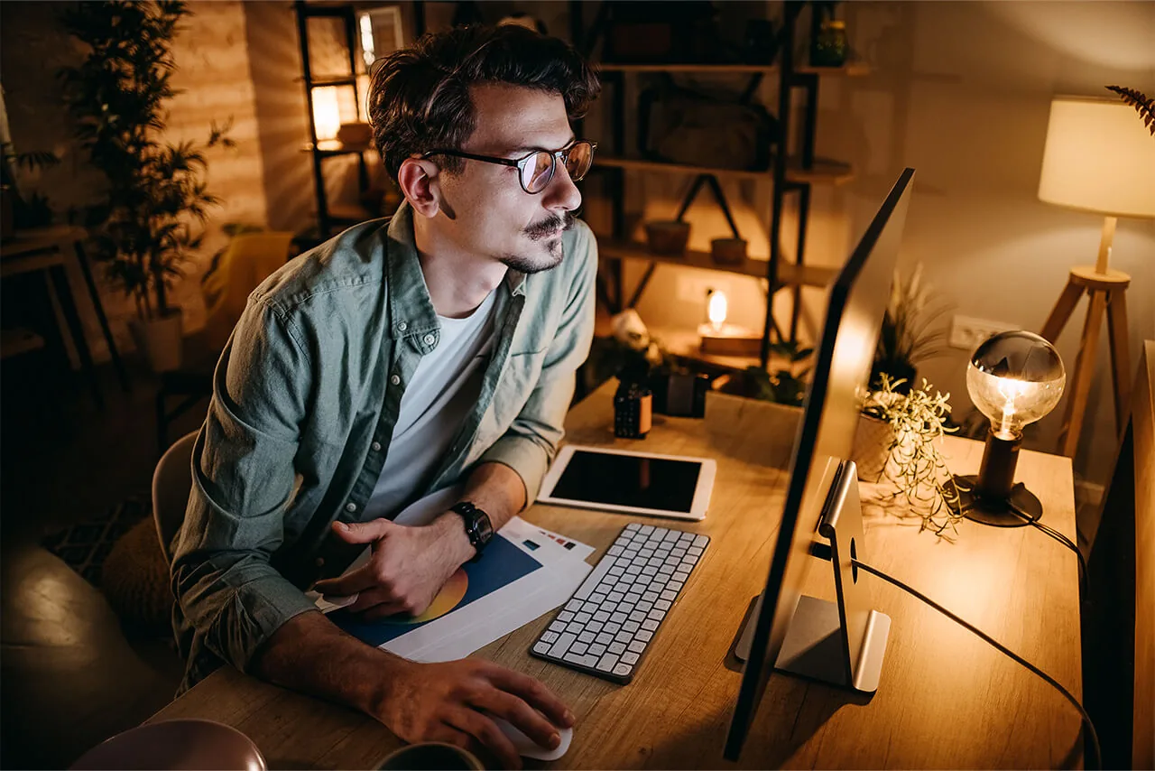 Man working at a desktop computer at home in the evening