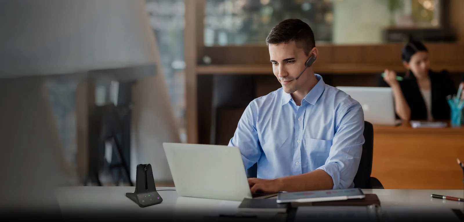 Office worker on a laptop with a Yealink WH63 DECT headset base on the desk