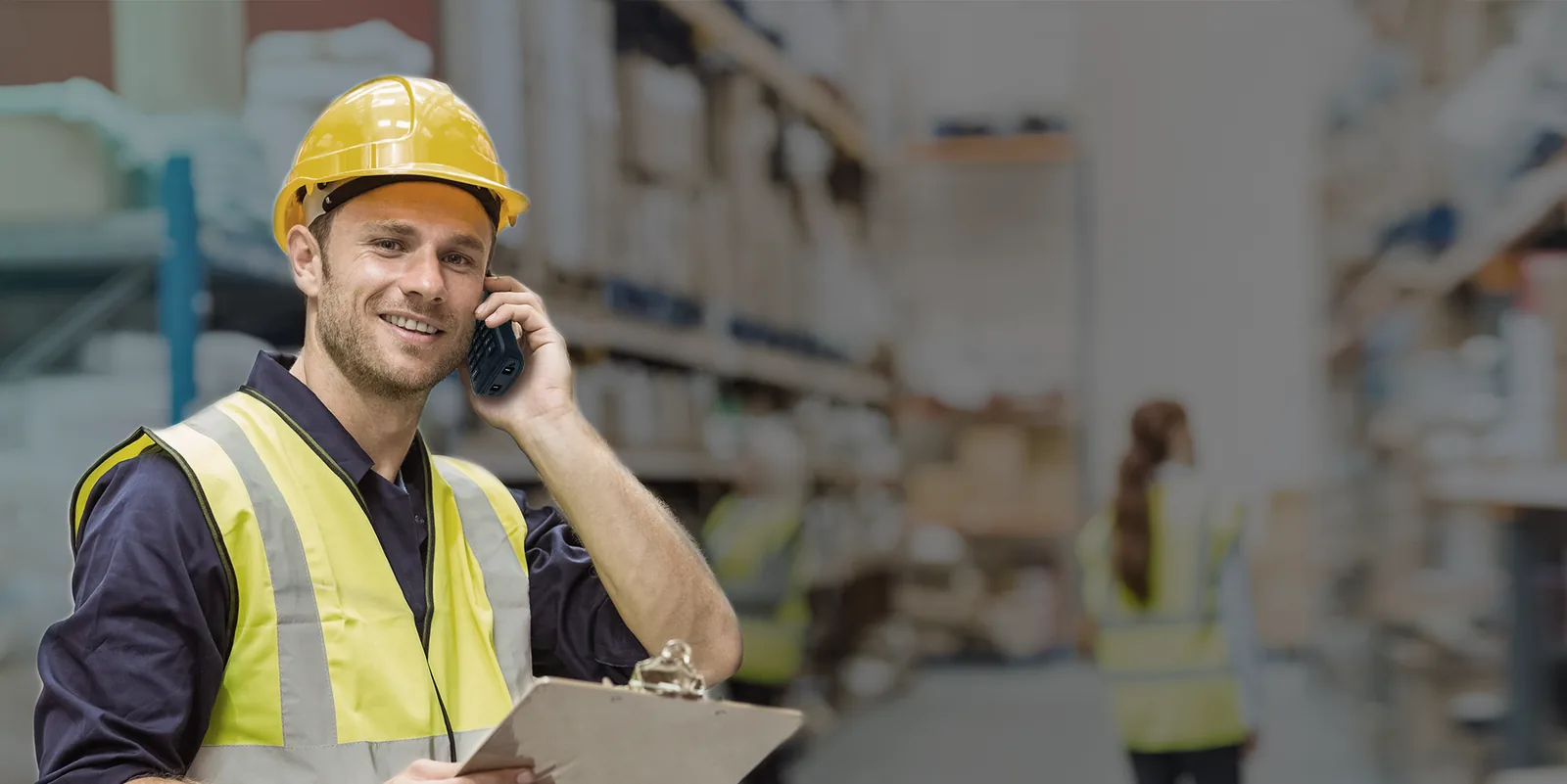 Warehouse worker in a hard hat on a call with a rugged Yealink DECT handset