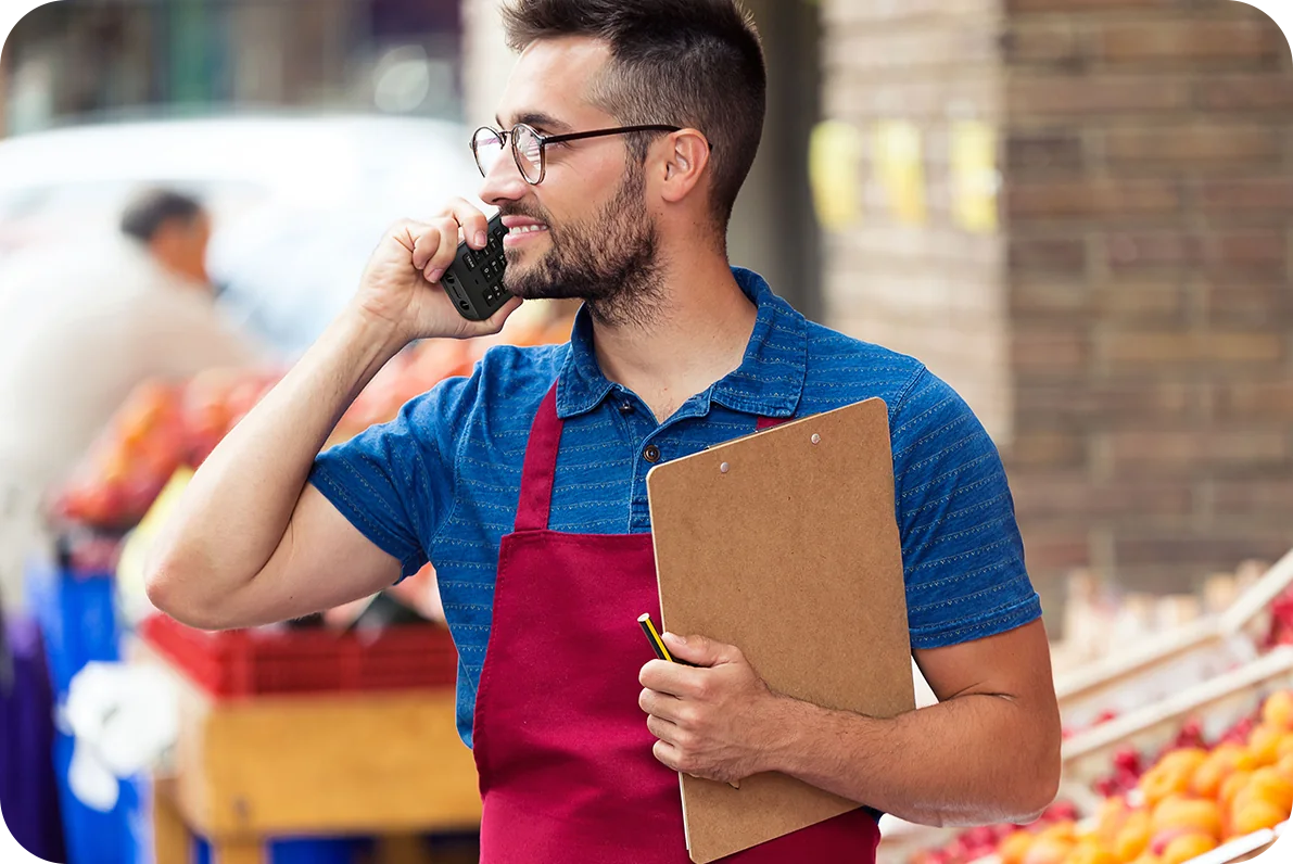 Shop-floor worker with a clipboard taking a call on a Yealink AX83H Wi-Fi handset