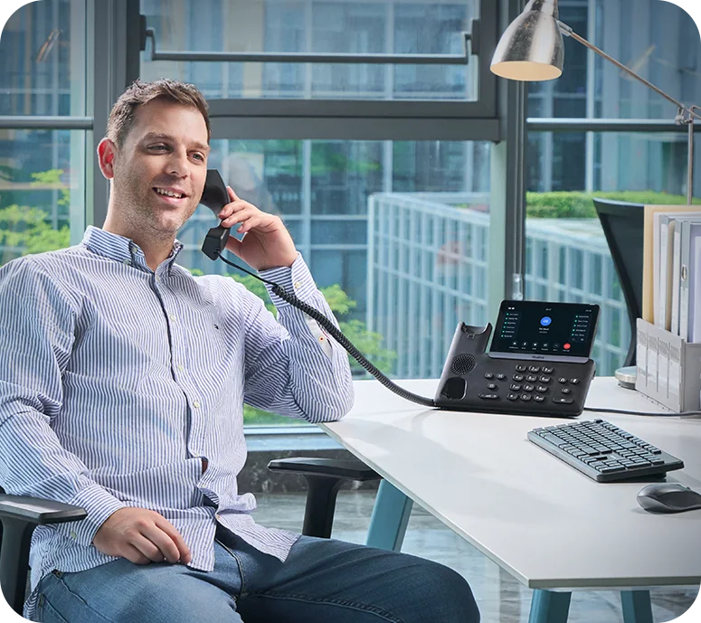 Man on a call at a Yealink SIP-T77U with 7-inch touch screen in a city office
