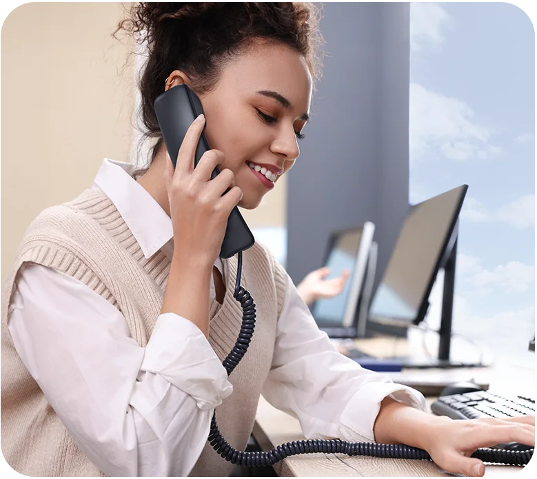 Office worker taking a call on the handset of a Yealink SIP-T73U desk phone