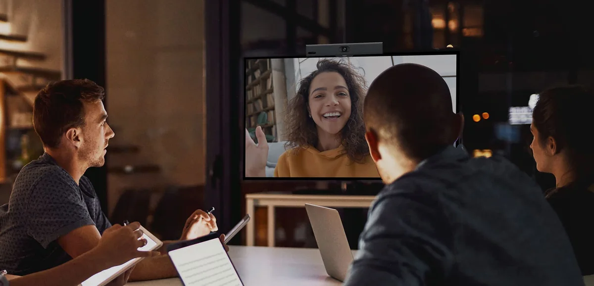 Colleagues on a hybrid video call in a small meeting room with a Yealink MeetingBar