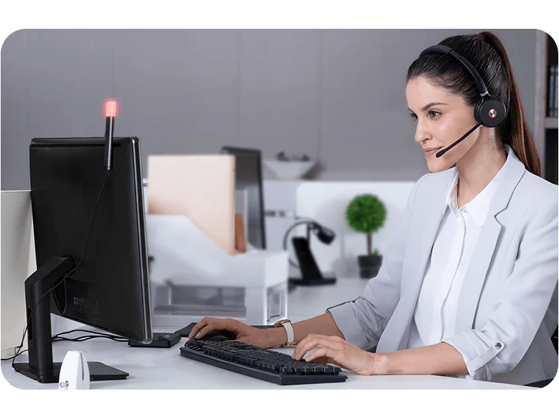 Worker in an open-plan office wearing a Yealink DECT headset with a BLT60 busylight on the monitor