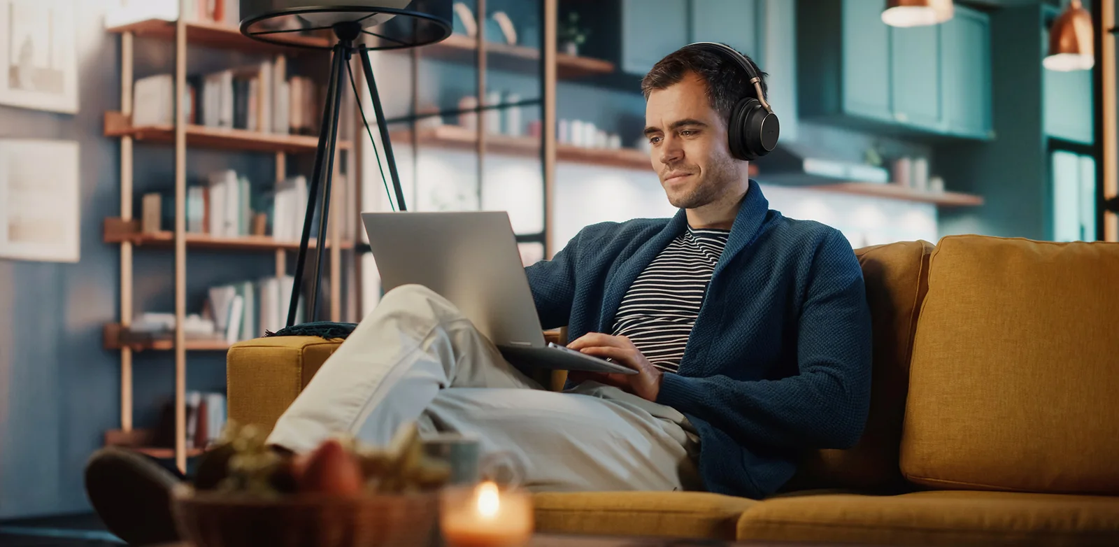Man working from home on a sofa with a laptop and a Yealink BH76 series Bluetooth headset
