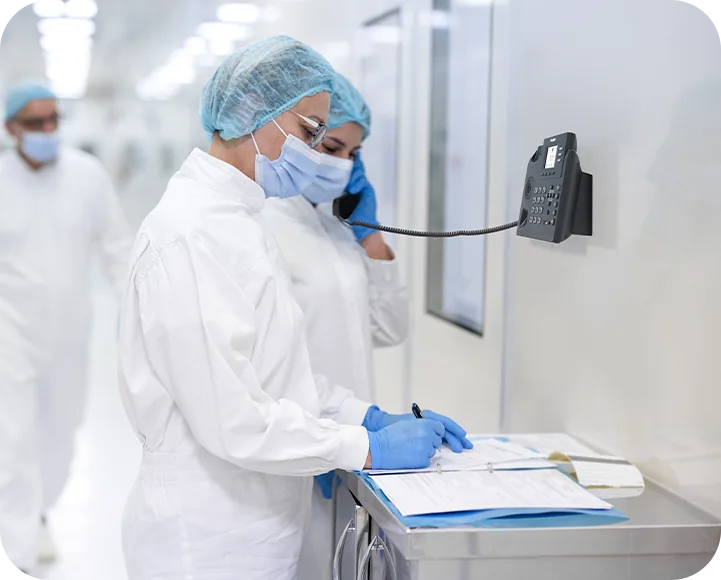 Laboratory worker in protective clothing using a wall-mounted Yealink MP52 E2 Teams phone